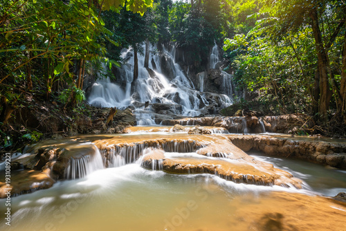Serene tropical Dai Chong Thong waterfall cascade over limestone rock in lush forest at Sangkhlaburi, Kanchanaburi, Thailand under soft morning light