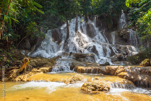Serene tropical Dai Chong Thong waterfall cascade over limestone rock in lush forest at Sangkhlaburi, Kanchanaburi, Thailand under soft morning light