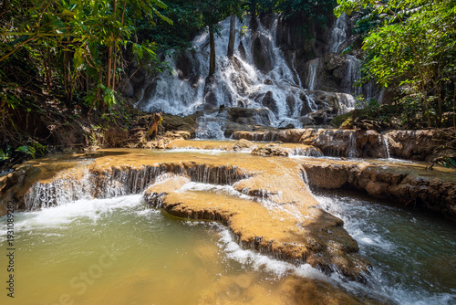 Serene tropical Dai Chong Thong waterfall cascade over limestone rock in lush forest at Sangkhlaburi, Kanchanaburi, Thailand under soft morning light
