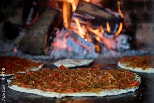Artisan pizza preparation with wood fired clay oven in rustic kitchen