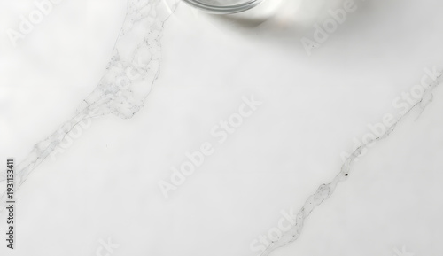 a minimal white Carrara marble slab, realistic grey veining pattern, soft natural daylight, a subtle shadow from an unseen glass bowl on the upper edge