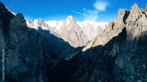 Majestic peaks rise against a vibrant blue sky, creating a breathtaking panorama of the high alpine landscape. The photograph captures the raw beauty of the mountain.