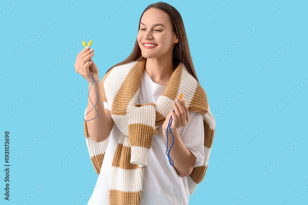 Obraz premium Young woman with ear plugs on blue background