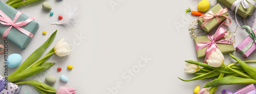 Easter eggs with tulip flowers and gift box on grey background
