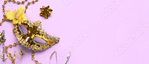 Beautiful golden carnival mask and beads on lilac background