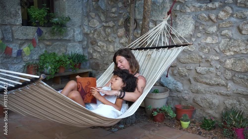 Mother and daughter reading a book in a relaxing hammock