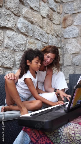 Mother teaching her child to play keyboard outdoors