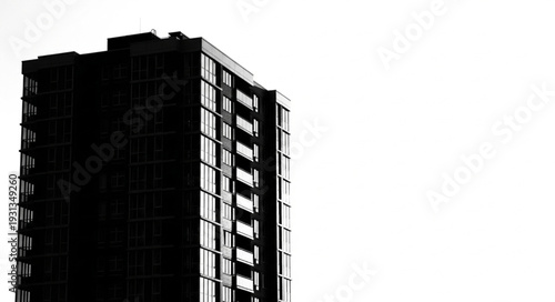 Modern high rise apartment building silhouette against bright sky.
