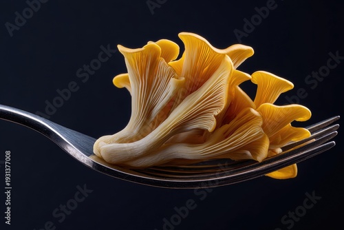 Golden Oyster Mushrooms Piled on a Silver Fork Against a Dark Background