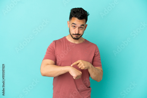 Obraz na plátně Young caucasian man isolated on blue background making the gesture of being late
