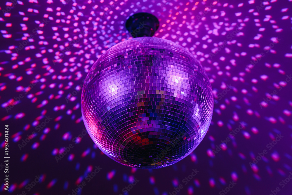 Fototapeta premium disco ball with mirror surface and bright rays, purple color, hanging on ceiling, night party background