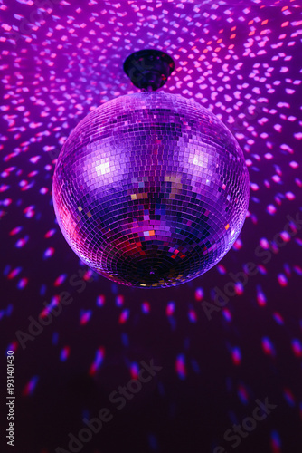 disco ball with mirror surface and bright rays, purple color, hanging on ceiling, night party background