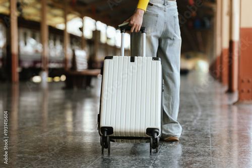 Stylish young woman traveling at train station with suitcase, traveling alone on vacation or business trip, enjoying summer city adventure.	
