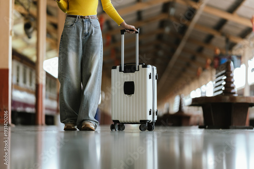 Stylish young woman traveling at train station with suitcase, traveling alone on vacation or business trip, enjoying summer city adventure.	