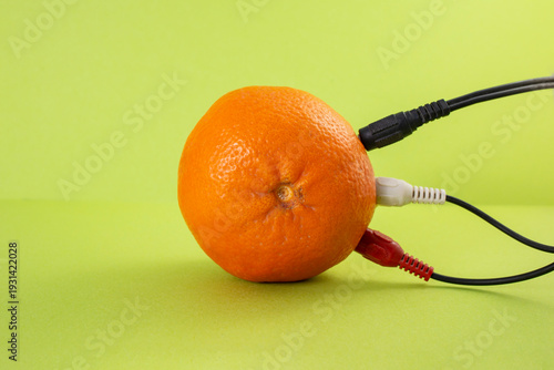 Colorful cables plugged in a orange on bright green background, abstract sustainable energy concept