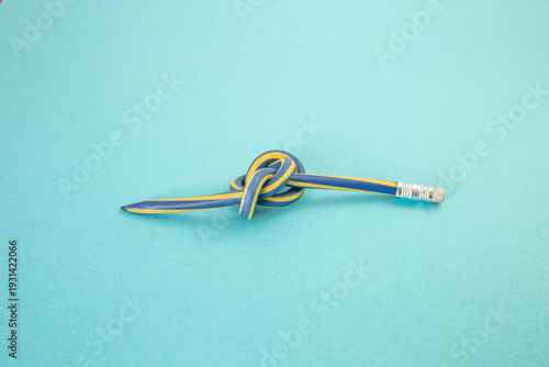 Flexible pencil crayon knot on bright blue background study stress concept
