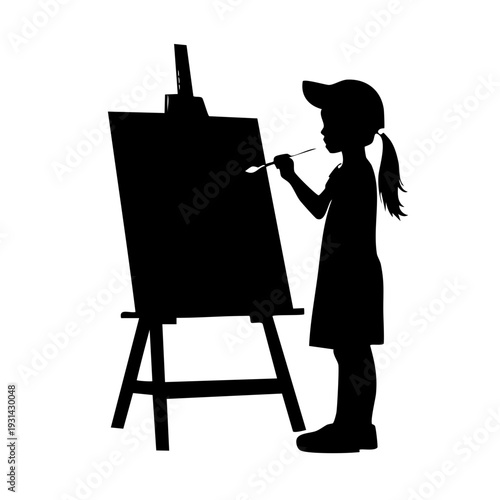 Young girl stands before easel painting with brush in hand in studio