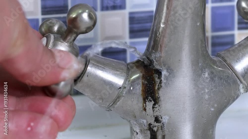 A damaged faucet on the washbasin is checked by a plumber with a water faucet in the bathtub. 4k video
