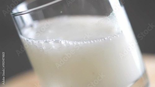 Close-up shot of a refreshing white fizzy drink or beer being poured into a transparent glass, creating abundant foam and bubbles. Dynamic flow and texture.