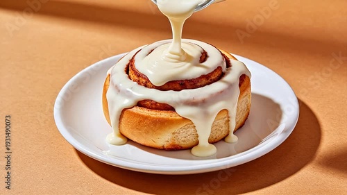 Cinnamon roll with icing being poured