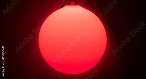Bright Red Sphere Illuminated Against Dark Background.