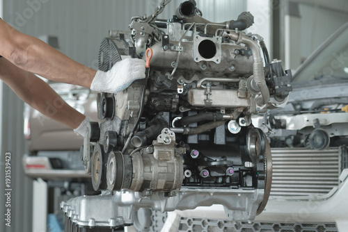 Car service center. The car mechanic moves the car engine after repair to the car for further installation.