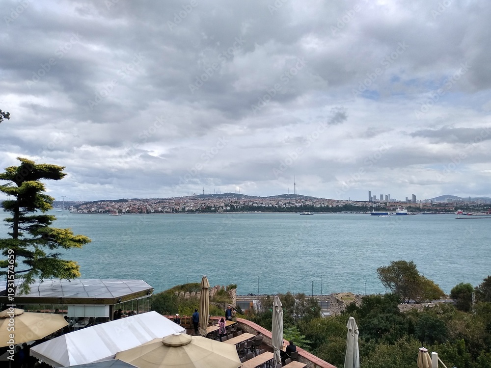 Fototapeta premium Scenic waterfront restaurant with city skyline view on cloudy day