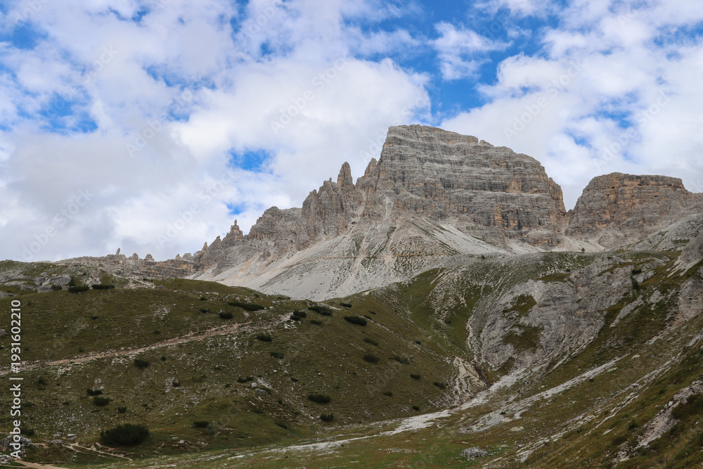 Fototapeta premium Dolomite peaks rising above alpine terrain with clouds passing gently across the ridges