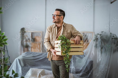 Tableau sur toile Happy man moving into new home carrying box