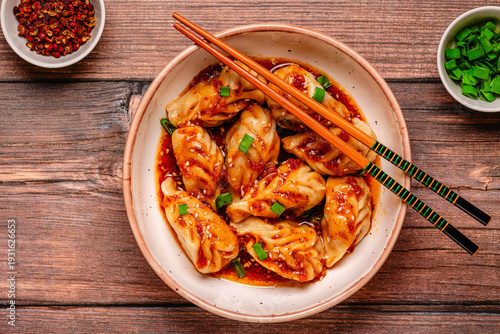 Delicious dumplings served in a bowl with a spicy sauce and green onions