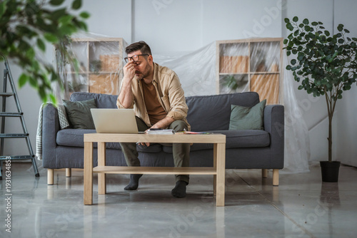 Konstfotografi Man feeling overwhelmed by home renovation and financial stress