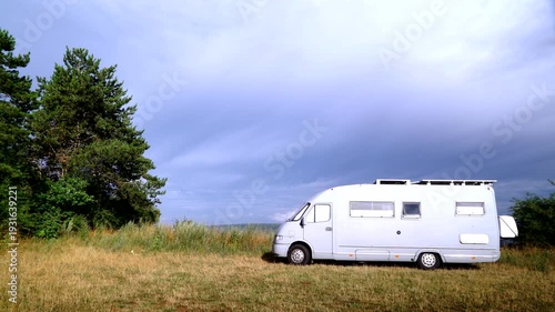 Time lapse of clouds moving over caravan camping on nature. Holidays, travel with motor home. 