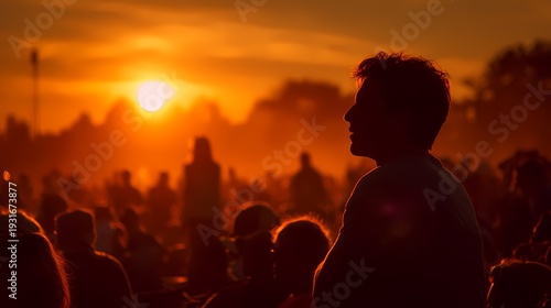 Silhouette of Person Against Vibrant Sunset in Crowded Outdoor Scene
