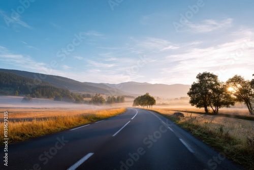 Scenic sunrise over misty countryside road with rolling hills and lush trees