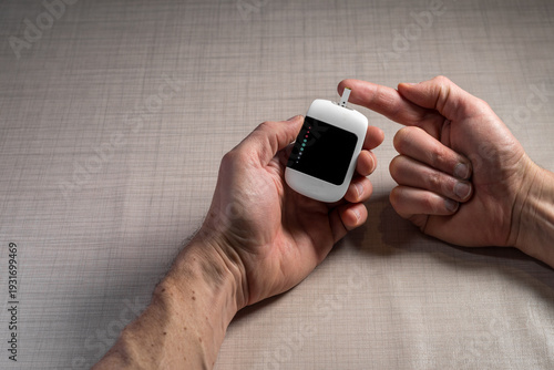 Close up of a man hands using a digital glucose meter to check blood sugar levels at home. Concept of diabetes management, medical self-testing, and healthcare monitoring for a healthy lifestyle.