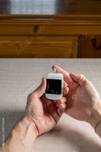 Close up of a man hands using a digital glucose meter to check blood sugar levels at home. Concept of diabetes management, medical self-testing, and healthcare monitoring for a healthy lifestyle.