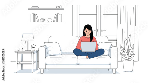 Young woman sitting cross-legged on a comfortable white sofa and working on her laptop in a bright and minimalist home office or living room.