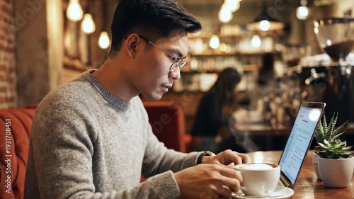 Man working on laptop in coffee shop, drinking coffee, thinking.