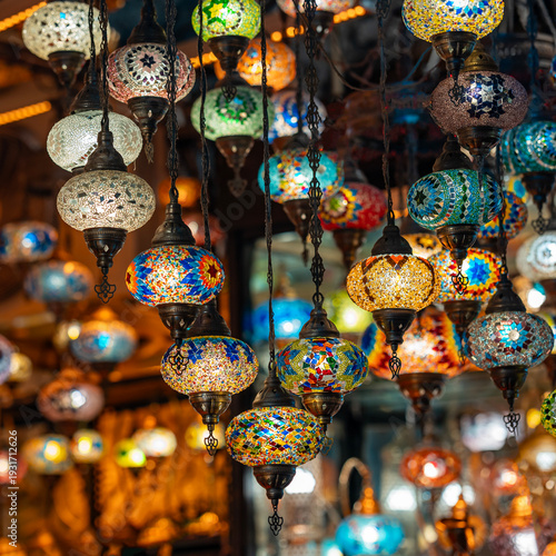 Colorful Turkish mosaic lamps hanging in a traditional market shop. Vibrant glass patterns and warm lighting create an atmospheric decorative scene ideal for design, interior and cultural themes.