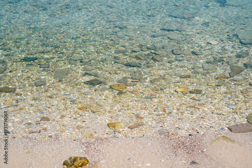 Photography Clear turquoise ocean water gently flows over the pebbly bottom under bright sun