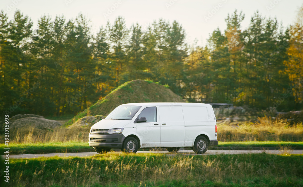 Fototapeta premium White vehicle on road beside green field