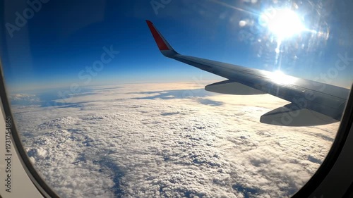 Airplane wing view from the window above the clouds.