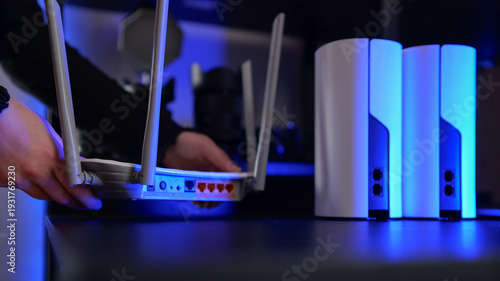 Vászonkép Hands setting up a modern Wi-Fi router and mesh system with blue ambient lightin