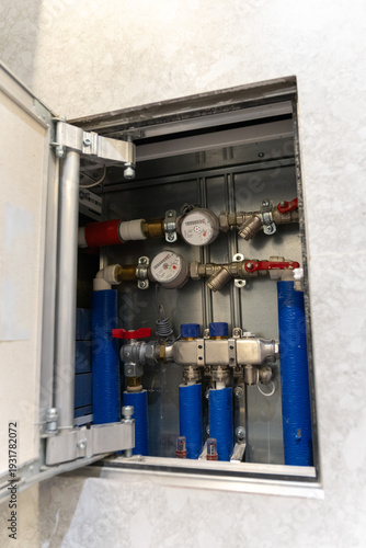 Water meters, pipe installation inside wall cabinet display residential plumbing system with gauges, valves and blue red hoses, Utility management and resource monitoring concept for housing services