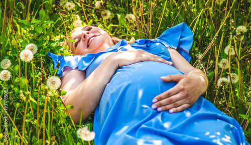 Pregnant woman with dandelions in the garden. Selective focus.