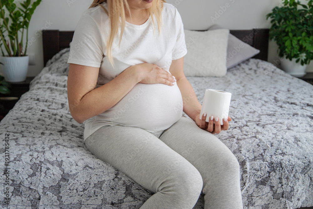 Fototapeta premium Pregnant woman holding toilet paper. Selective focus.