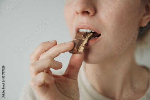 Close up of woman biting chocolate bar, sweet craving and sugar addiction concept