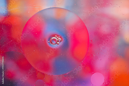 Close-up of the movement of oil droplets on the water surface. Colorful abstract macro background of oil drops on the water surface.