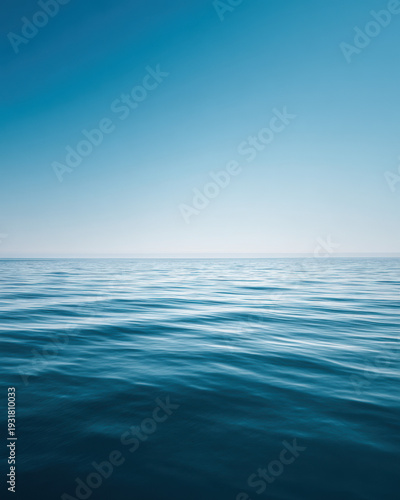 Calm blue ocean surface under clear sky with gentle waves, minimal seascape background for relaxation and summer concept.