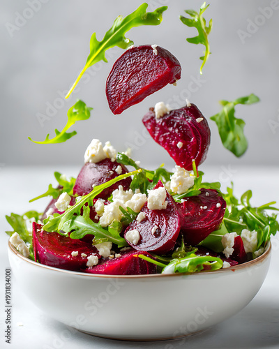 Fresh and Healthy Arugula Salad with Beets and Feta Cheese Flying in the Air on Light Grey Background